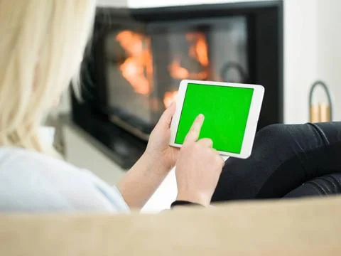 Young woman using tablet computer in front of fireplace beautiful young wo... Stock Photos