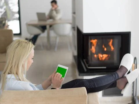 Young woman using tablet computer in front of fireplace beautiful young wo... Stock Photos