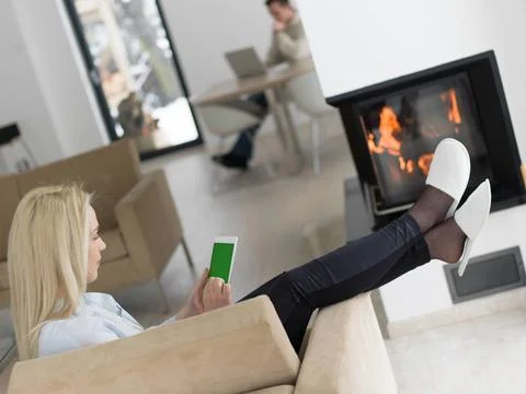 Young woman using tablet computer in front of fireplace beautiful young wo... Stock Photos