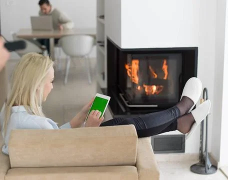 Young woman using tablet computer in front of fireplace beautiful young wo... Stock Photos