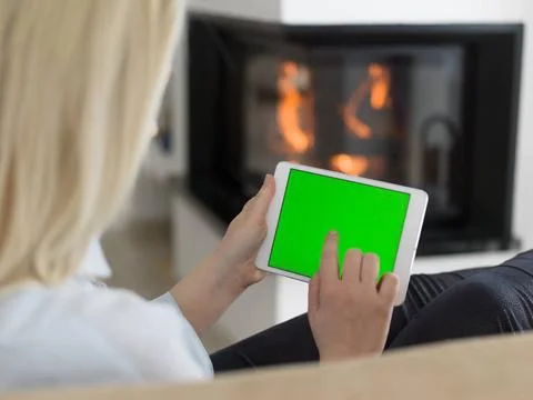 Young woman using tablet computer in front of fireplace beautiful young wo... Stock Photos