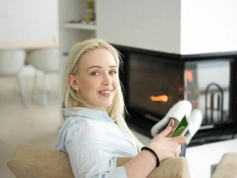 Young woman using tablet computer in front of fireplace beautiful young wo... Stock Photos