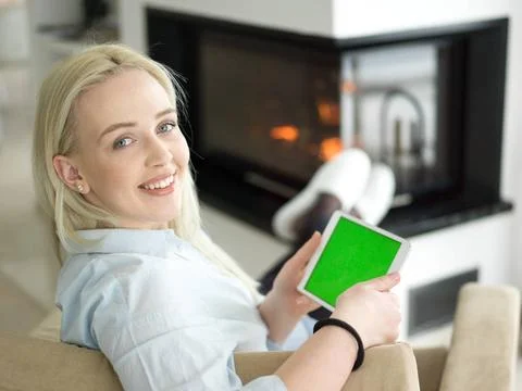 Young woman using tablet computer in front of fireplace beautiful young wo... Stock Photos