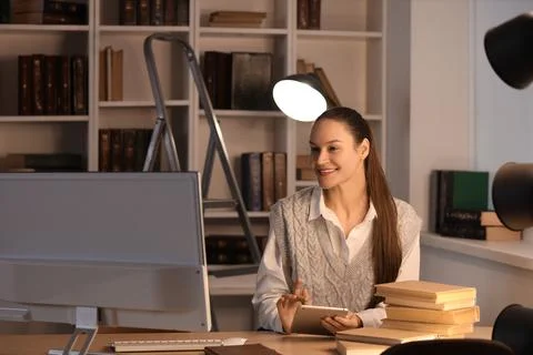 Young woman using tablet computer in library at night Stock Photos