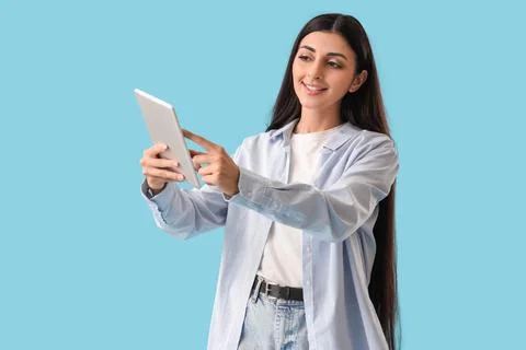 Young woman using tablet computer on blue background. Search concept Foto stock