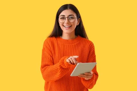 Young woman using tablet computer on yellow background. Search concept Stock Photos