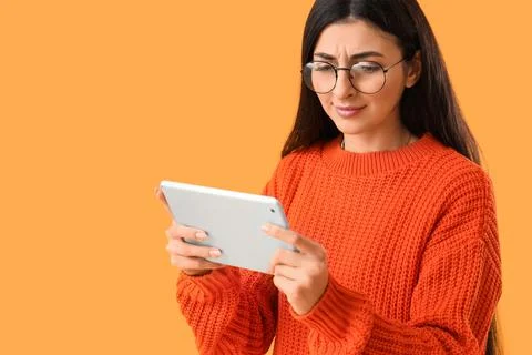 Young woman using tablet computer on yellow background. Search concept Stock Photos