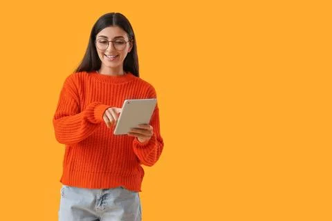 Young woman using tablet computer on yellow background. Search concept Stock Photos