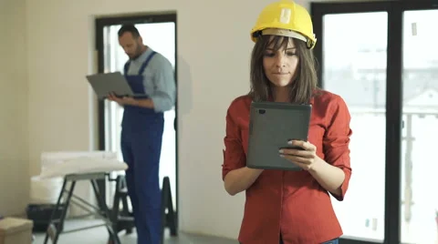 Young woman using tablet at her new home, male worker in the background Stock Footage 63994616