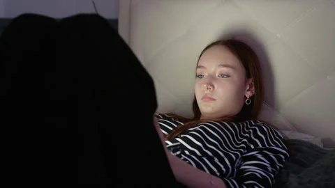 Young woman using tablet lying in bed in the dark Stock Footage 310765887