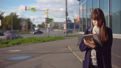 Young woman is using tablet next to an office building amid crossroads. Stock Footage 116195447