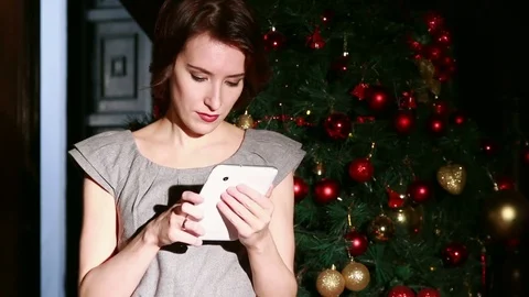 Young woman using tablet PC in front of Christmas tree. Video stock 70803869