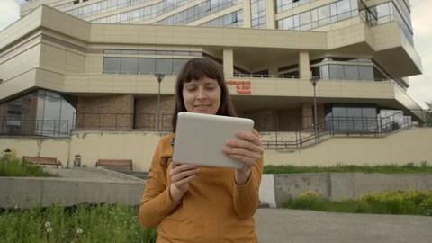 Young woman using a tablet standing on the background of an office building. Vídeos de archivo 76937912
