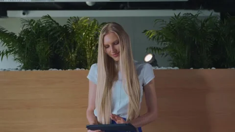 Young woman using tablet while seated on wooden tribune in office Stock Footage 340257164