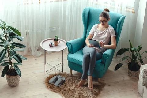 Young woman using tablet while sitting in a comfortable chair Stock Photos