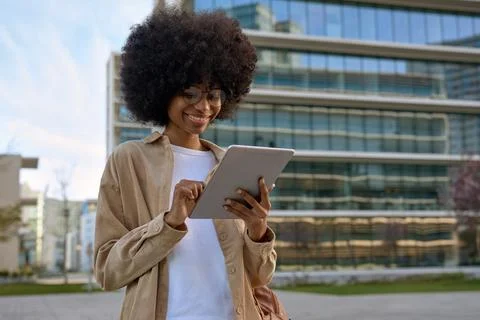 A young woman using touchscreen of tablet standing in front of buildings. Stock Photos