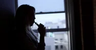 Young Woman Using Vaporizer Silhouetted Next To Hallway Window 4K Stock Footage