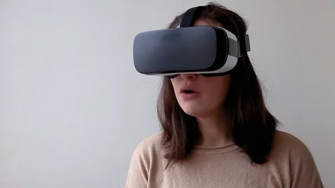 Young woman using virtual reality VR glasses helmet headset on white background Stock Footage 124969864