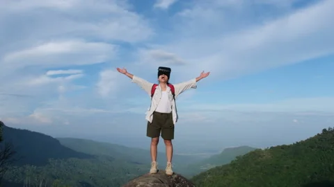 Young woman using virtual reality glasses stands on a cliff on top of a mountain Видео 196276591
