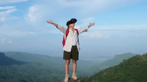 Young woman using virtual reality glasses stands on a cliff on top of a mountain Stock Footage 196276962