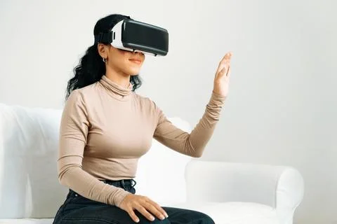 Young woman using virtual reality VR goggle at home for crucial experience Stock Photos