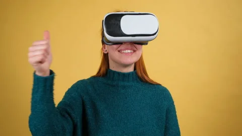 Young woman using VR app headset helmet. Isolated on yellow background in studio Stock Footage 150112151