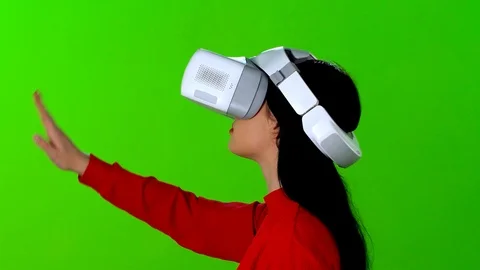 Young woman using a VR application or game, over green screen. 스톡 동영상 119546203
