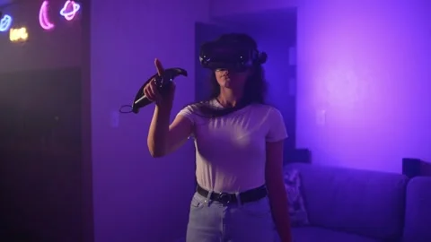 Young woman using VR controllers exploring virtual reality experience at home Stock Footage 333725731