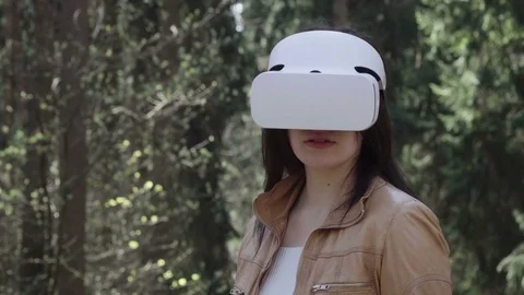 Young woman using vr headset and turning head in forest Stock Footage 74762143