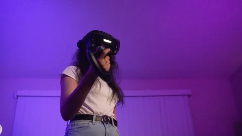 Young woman using VR headset pointing controller exploring virtual environment Stock Footage 333726622