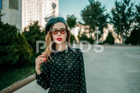 Young woman in vintage black polka dot dress posing outside Stock Photos