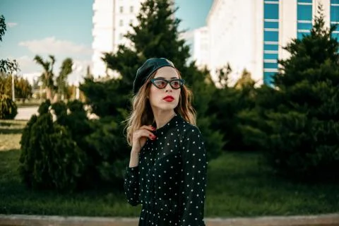 Young woman in vintage black polka dot dress posing outside Stock Photos