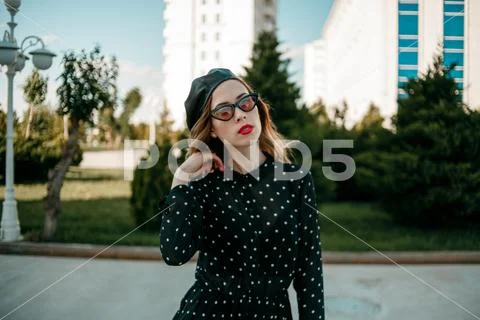 Young woman in vintage black polka dot dress posing outside Stock Photos