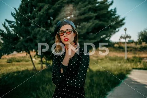 Young woman in vintage black polka dot dress posing outside Stock Photos