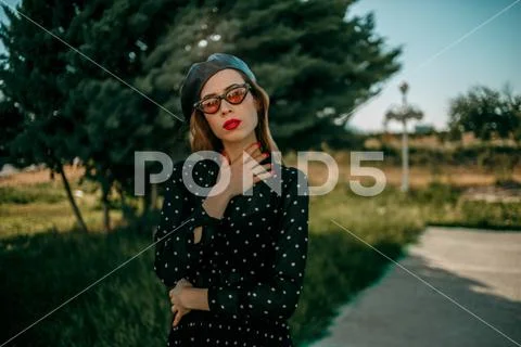 Young woman in vintage black polka dot dress posing outside Stock Photos