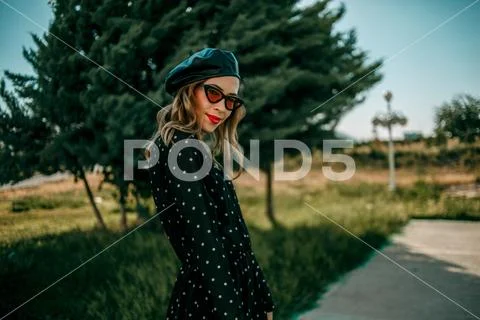 Young woman in vintage black polka dot dress posing outside Stock Photos