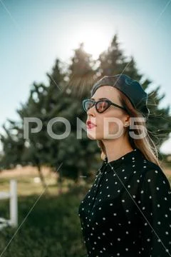 Young woman in vintage black polka dot dress posing outside Stock Photos