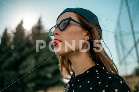 Young woman in vintage black polka dot dress posing outside Stock Photos