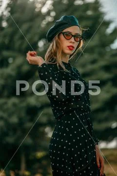 Young woman in vintage black polka dot dress posing outside Stock Photos