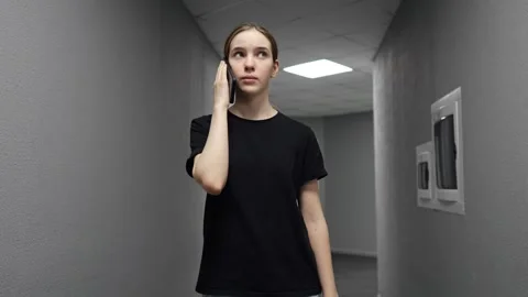 Young woman walking and talking on phone in corridor 库存影片 330102953