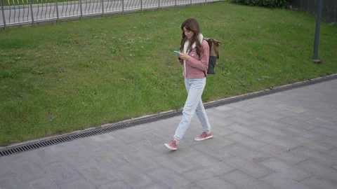 Young woman walking and using smartphone on the street Stock Footage 293479005