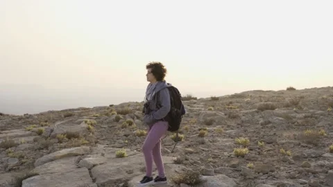 Young woman walking with backpack hiking and traveling in desert mountain Stock Footage 143641553