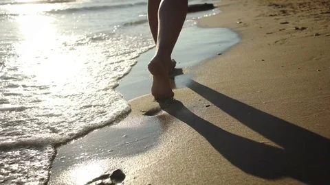 Young woman walking on beach in sea waves during sunset. Medium shot. Stock Footage