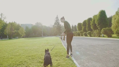 Young woman walking with her stubborn dog at the alley near park 4K Stock Footage