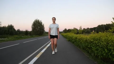 Young woman walking on sidewalk and transitioning into running at sunset 库存影片 329574853