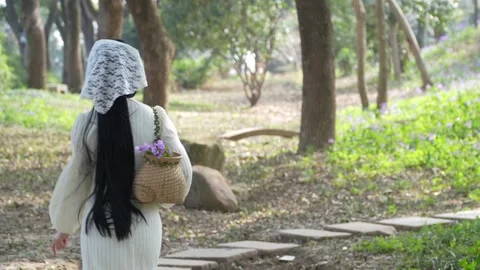 Young woman walking through a forest park with a flower basket Stock Footage 342248016