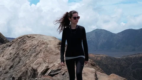 Young woman walks along Mount Bromo volcano crater edge in slow motion in Java Stock Footage