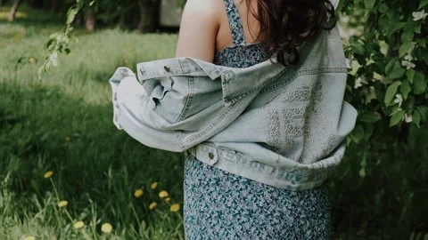 A young woman walks through a blooming apple orchard on a sunny day. Stock Footage 199240953