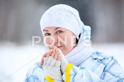 Young woman warming fingers with ski poles in hands Stock Photos