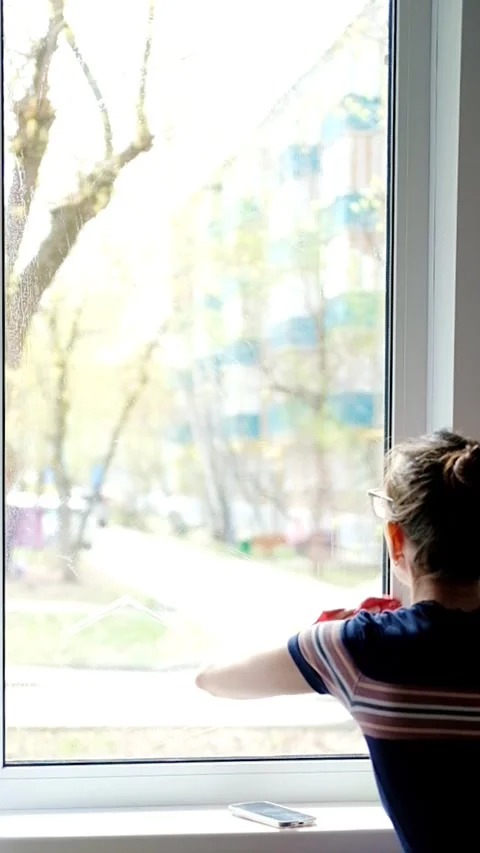 Young woman washes a window on the first floor with a rag in her hand, close-up Stock Footage 273785992
